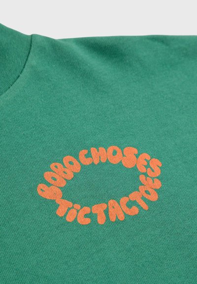 T-shirt verde in cotone, con una grafica rotonda arancione "BORACHOSES TACTACTUES". Tessuto morbido con design a collo rotondo.