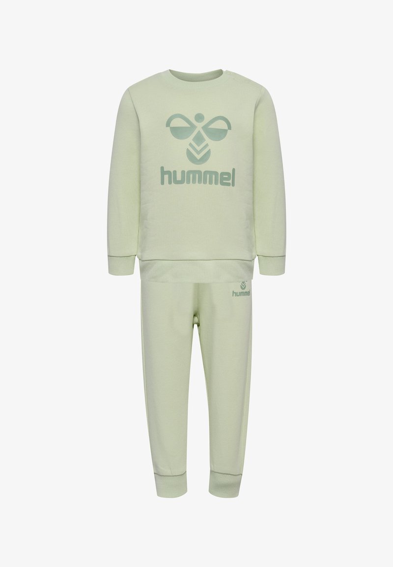 Jasnozielony zestaw z dresu, składający się z bluzy i spodni, z dużym logo "hummel" w ciemniejszym zielonym kolorze. Wykonany z miękkiego materiału, z ściągaczami przy mankietach i w pasie.