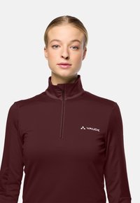 Burgunderfarbener Langarm-Halfzip-Pullover aus weichem Stoff, mit hohem Kragen und einem weißen VAUDE-Logo auf der linken Brust.