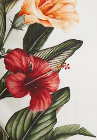 Floral fabric featuring large orange and red hibiscus flowers with green leaves on a white background, showcasing detailed textures and patterns.