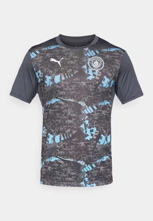 Maglia a maniche corte grigia con motivi astratti neri e blu, con logo Puma ed emblema del Manchester City sul petto.
