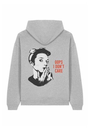 Sweatshirt gris avec un graphique noir représentant une femme avec un nœud et le texte "OUPS JE ME FOUS DE TOUT" en orange, offrant une coupe décontractée et des poignets côtelés.
