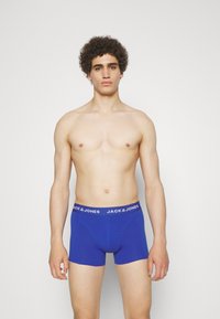 Blaue Boxer-Shorts mit einem weißen Bund, auf dem das Logo "JACK & JONES" zu sehen ist. Der Stoff wirkt glatt und hat ein körpernahes Design.