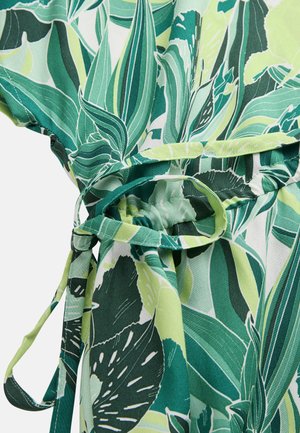 Groen en lichtgroen tropisch bladpatroonstof met een gestrikte tailleceintuur en geplooide details op de kleding.