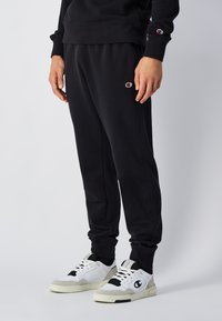Sorte sweatpants lavet af en bomuldsblanding, med en tapered fit, elastisk talje og sidelommer. Accentueret med et lille broderet logo.