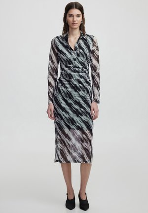 Vestido cruzado en una tela fluida con un patrón abstracto en negro, blanco y azul. Con cuello, mangas largas y longitud hasta la mitad de la pantorrilla.