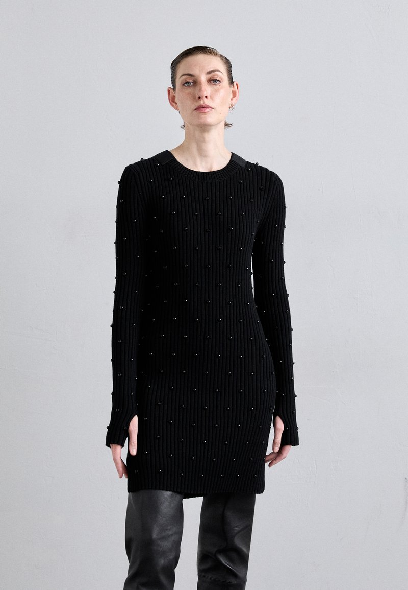 Abito maglione nero a coste con superficie testurizzata e dettagli in perle, colletto rotondo e maniche lunghe con spacco laterale.