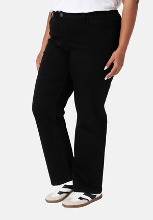 Zwarte denim broek met een rechte pijpdesign, vijfzakkenstijl, riemlussen en metalen knoopsluiting, gedragen met witte en zwarte sneakers.