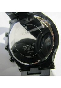 Schwarzer Edelstahl-Uhrenboden mit gravierten Details, einschließlich wasserdichter Bewertung, Modellnummer und Markenlogo.