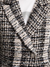 Giacca doppiopetto in un tessuto intrecciato nero e crema con texture; presenta bottoni metallici e un classico design con rever.