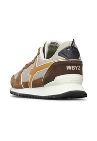 Sneaker marrone e beige con striscia gialla senape, targhetta nera in gomma sul tallone e sole bianca, con il logo "W6YZ" sul tallone e sulla linguetta.