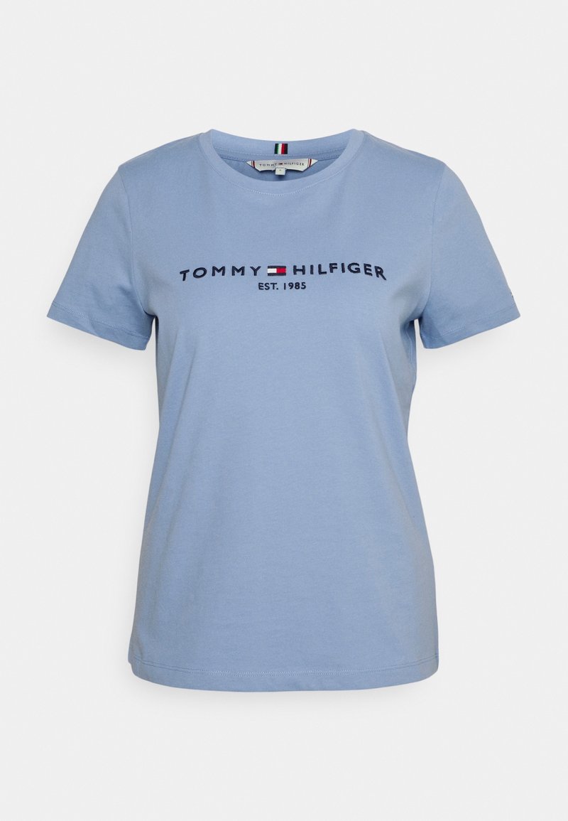 Světle modré krátké rukávy bavlněné tričko s nápisem "Tommy Hilfiger EST. 1985" a malou červenou, bílou a námořnickou modrou nášivkou na hrudi.
