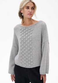 Jasnoszary sweter z dzianiny o luźnym kroju, z teksturowanym wzorem wypukłych kropek z jednej strony oraz szerokimi rękawami. Miękka, teksturowana tkanina.