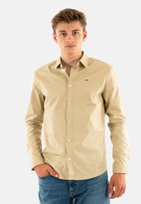 Camicia beige a maniche lunghe in cotone con vestibilità slim, caratterizzata da un colletto classico, maniche lunghe e un piccolo logo sul lato sinistro del petto.