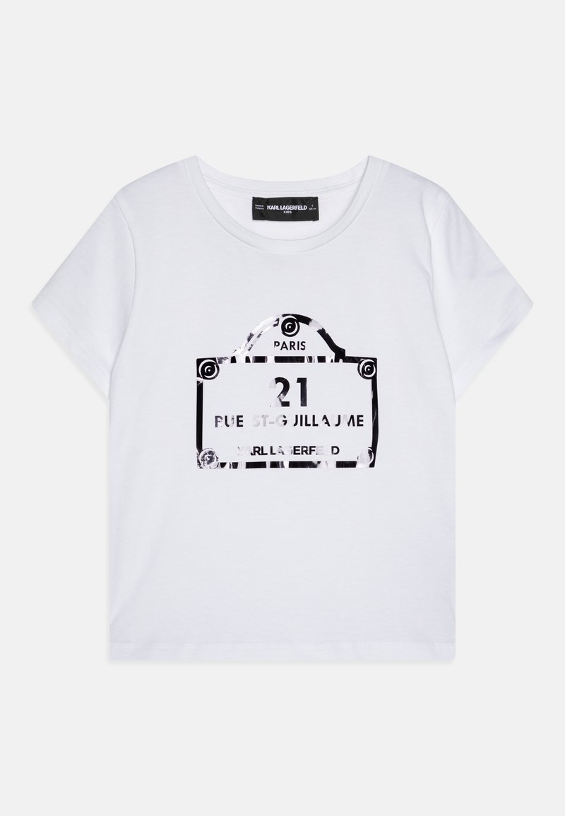 T-shirt en coton blanc avec un imprimé graphique noir d'un panneau de rue parisien affichant le texte « 21 rue St. Guillaume » et un logo. Manches courtes, col rond.