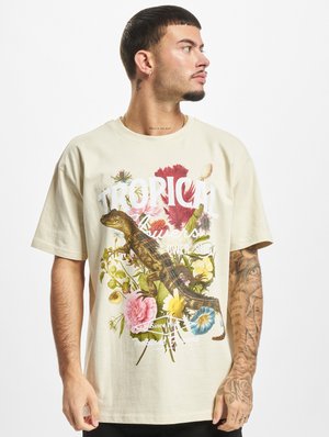 Beige cotton t-shirt featuring a vibrant tropical graphic with flowers and a lizard. Short sleeves, crew neck, relaxed fit.