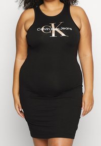 Svart klänning i ärmlös modell gjord av stretchigt material, med en figurnära silhuett. "Calvin Klein Jeans" logotyp i vitt och roséguld över bröstet.