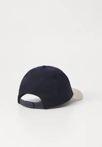 Marinekasket med en beige skygge, lavet af bomuld. Har et klassisk design, justerbar snaplukning og syede ventilationshuller.