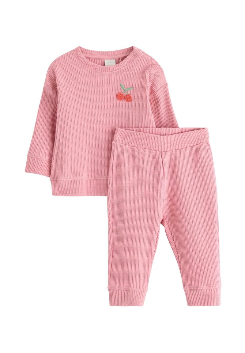 Lyserødt ribbet strik loungewear-sæt bestående af en langærmet top med kirsebærbroderi og matchende bukser med elastik i taljen.