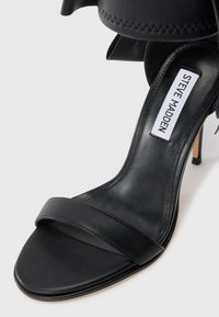 Black high-heeled sandal made of smooth leather, featuring a single wide strap across the toe and a stacked stiletto heel.