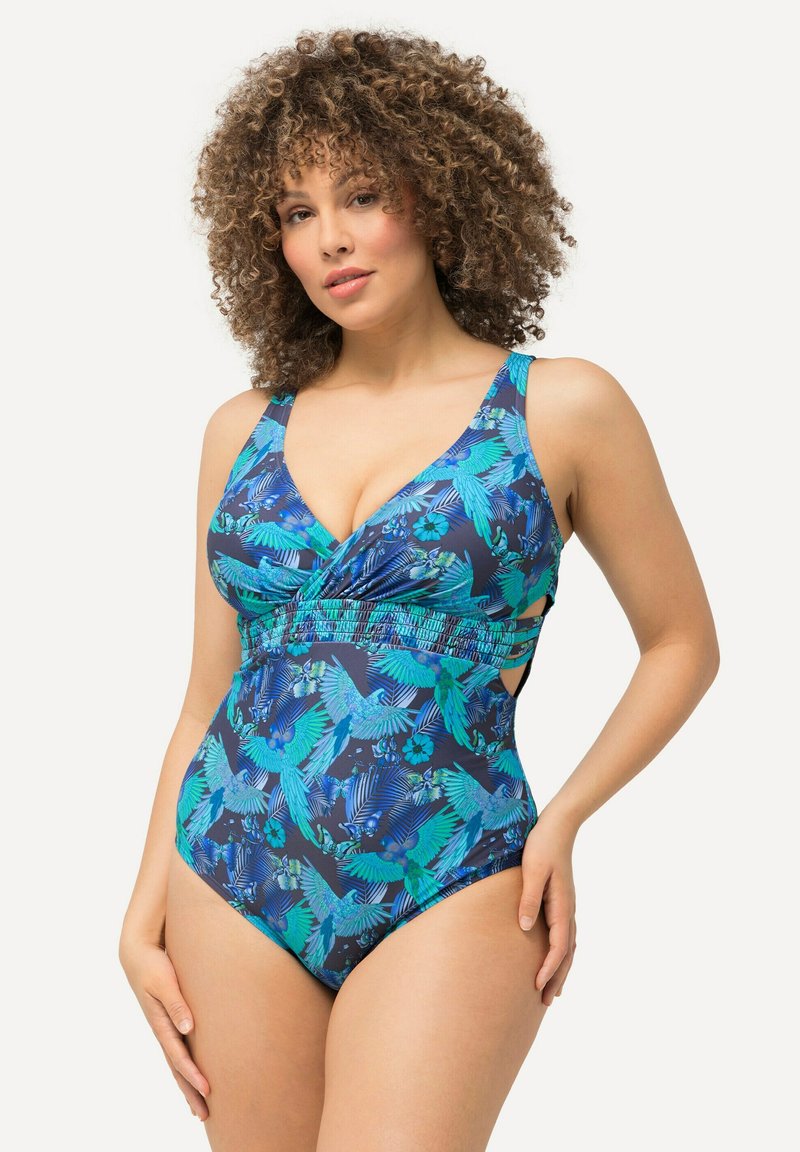 Maillot de bain à design enveloppant, avec un fond bleu marine et un motif vibrant d'oiseaux et de fleurs dans des nuances de bleu et de vert. Bretelles ajustables.