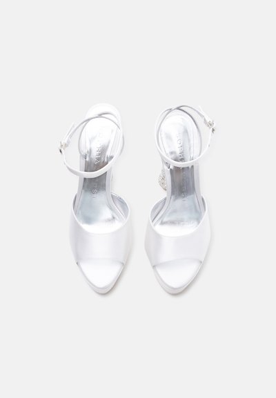 Λευκά σατέν πέδιλα με ανοιχτή μύτη, λουριά στον αστράγαλο και αγκράφες, από ψηλά σε απλό λευκό φόντο.