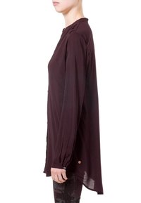 Blouse à manches longues en bordeaux profond, fabriquée dans un tissu léger avec une coupe décontractée. Comprend des accents de boutons aux poignets et un détail de pli au dos.