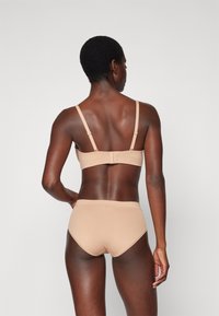 Beige underwear set including a bra with adjustable straps and a hook closure, paired with high-waisted briefs, both featuring a smooth texture.