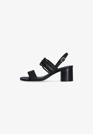 Sandalo con tacco in pelle nera, design open-toe, cinturino alla caviglia con fibbia e dettaglio annodato sul davanti.