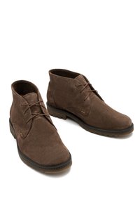Brązowe zamszowe botki za kostkę z okrągłymi noskami, sznurowane, o fakturowanej powierzchni. Gumowa podeszwa z delikatnym bieżnikiem dla lepszej przyczepności.