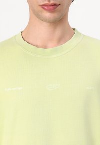 Light green cotton T-shirt with a crew neckline. Features white embroidered logo and text "arkk copenhagen est 2015" on the front.