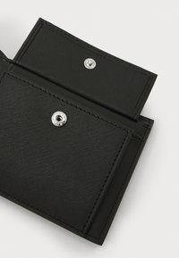 Μαύρο πορτοφόλι φτιαγμένο από υλικό με υφή, με κλείσιμο τύπου κουμπί και λείο ασημένιο χαρακτηριστικό. Περιέχει δύο διαμερίσματα με μινιμαλιστικό σχέδι�ο.