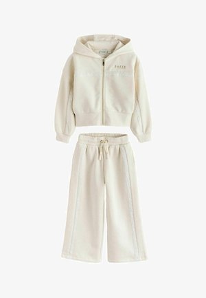 Cream-colored hoodie and wide-leg sweatpants set with lace trim down sleeves and pant legs, featuring front zipper and drawstring waist.