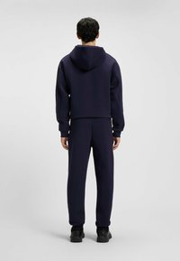 Chándal azul marino que incluye una sudadera con capucha y pantalones a juego, hecho de una tela suave con un corte relajado y puños acanalados.