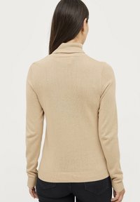Beige leichter Pullover mit hohem Kragen, langen Ärmeln und geripptem Saum. Weiche Textur, schlichtes Design, keine sichtbaren Muster oder Akzente.