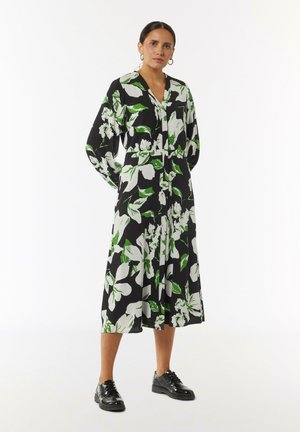Schwarzes, blumiges Midikleid mit großen weißen und grünen Blumenmustern; ausgestattet mit einer Knopfleiste, V-Ausschnitt und langen Puffärmeln.