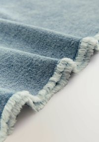 Heledsinine denimpind materjal frreeritult servadega, tekstuuriga pinnaga ja pehme viimistlusega, volditud, et näidata värvigraadi ja kude mustrit.
