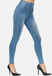 Jeans de tiro alto en azul con una textura suave, que presentan un cierre de múltiples botones, bolsillos frontales y un detalle desgastado en el muslo.