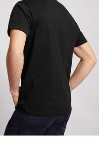 Černé bavlněné tričko s krátkým rukávem, jednoduchý design, fitted střih a kulatý výstřih. Má hladkou texturu a minimální detaily.