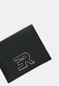 Portafoglio in pelle nera con superficie testurizzata, forma quadrata e accento in metallo con logo prominente. Design compatto, stile minimalista.