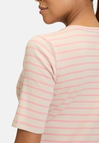 Lightweight ribbed top with short sleeves, featuring horizontal stripes in soft pink on a cream background. Round neckline, fitted design.