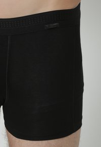 Zwarte katoenen boxershorts met een geweven elastische tailleband en een gladde, aansluitende pasvorm. Heeft platte naden en een basis snit.