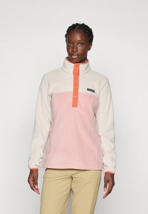 Fleece-pullover i ljuskräm och pastellrosa, med hög krage, knappstängning och en logopatch på bröstet.