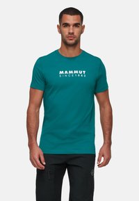 Teal korte mouw t-shirt met het woord "MAMMUT" en "SINCE 1862" in witte letters over de borst, gemaakt van een gladde stof.
