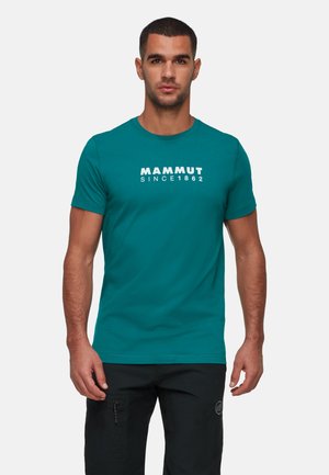 T-shirt manches courtes bleu-vert avec le mot "MAMMUT" et "SINCE 1862" en lettres blanches sur la poitrine, fabriqué en tissu lisse.
