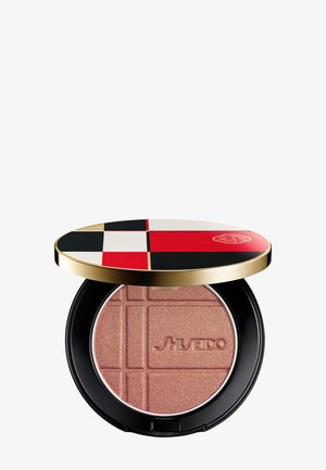 Kompaktes Puderrouge mit einem schwarzen, roten, weißen und beigen karierten Deckel sowie eingeprägtem Markennamen auf dem roségold schimmernden Puder.