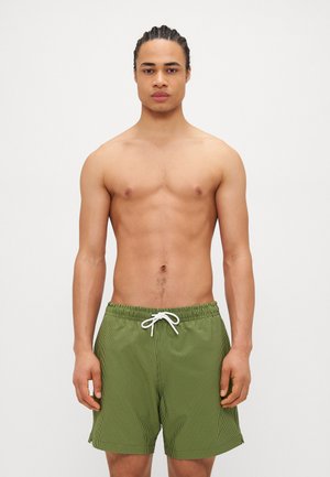 Shorts de bain rayés verts avec une taille élastique et un cordon blanc. Tissu léger, design jusqu'aux genoux et poches latérales.