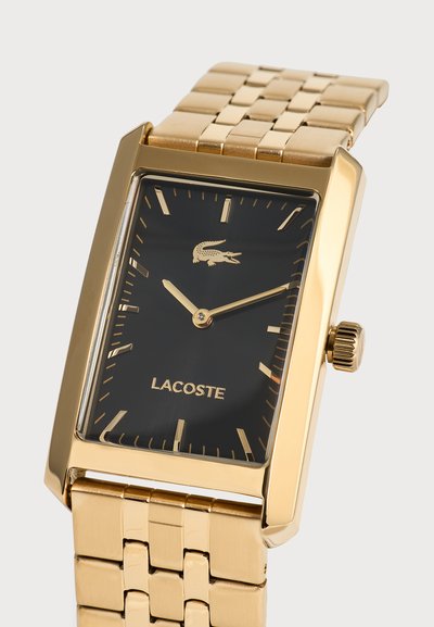 Ръчен часовник Lacoste в златист тон с правоъгълен черен циферблат, златисти стрелки и часови маркери и метална верижка от свързани звена.