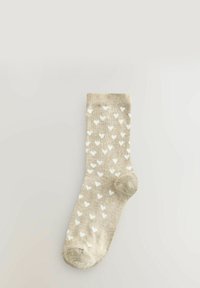 Beige Stricksocke mit weißen Herzmustern; ausgestattet mit einem Bündchen, verstärkter Zehenpartie und einer weichen Textur für zusätzlichen Komfort.