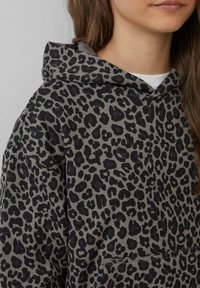 Grau mit schwarzen Flecken bedruckter Kapuzenpullover im Leopardendesign, mit Kordelzug-Kapuze und vorderer Kängurutasche, aus weichem Baumwollmaterial gefertigt.